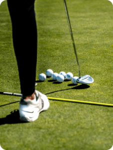 Golfer scooping ball with club.